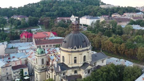 drohne fliegt bei sonnenuntergang über der kuppel einer kathedrale in lemberg, ukraine, umgeben von europäischen gebäuden