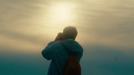 photographer capturing sunrise/sunset view from mountain top