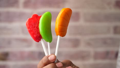 tres piruletas de colores sostenidas en una mano