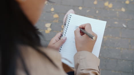 mujer escribiendo en un cuaderno al aire libre