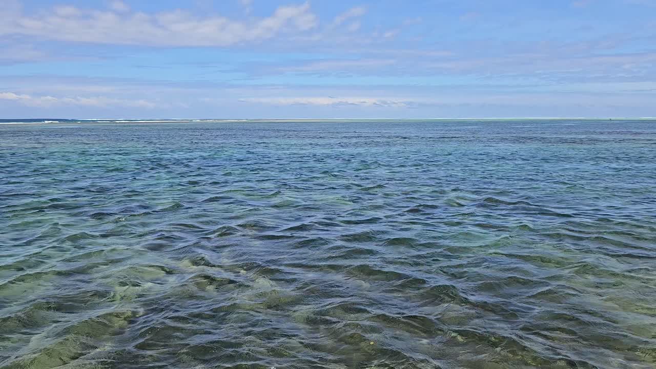 피지 해안의 태평양, 부분적으로 구름이 가득한 하늘 아래 평온하고 은 물을 특징으로합니다.