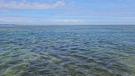 pacific ocean off the coast of fiji, featuring calm, clear waters under a partly cloudy sky