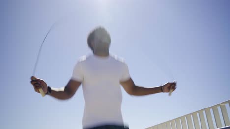 Bottom-view-of-African-American-man-skipping-rope-outdoor.