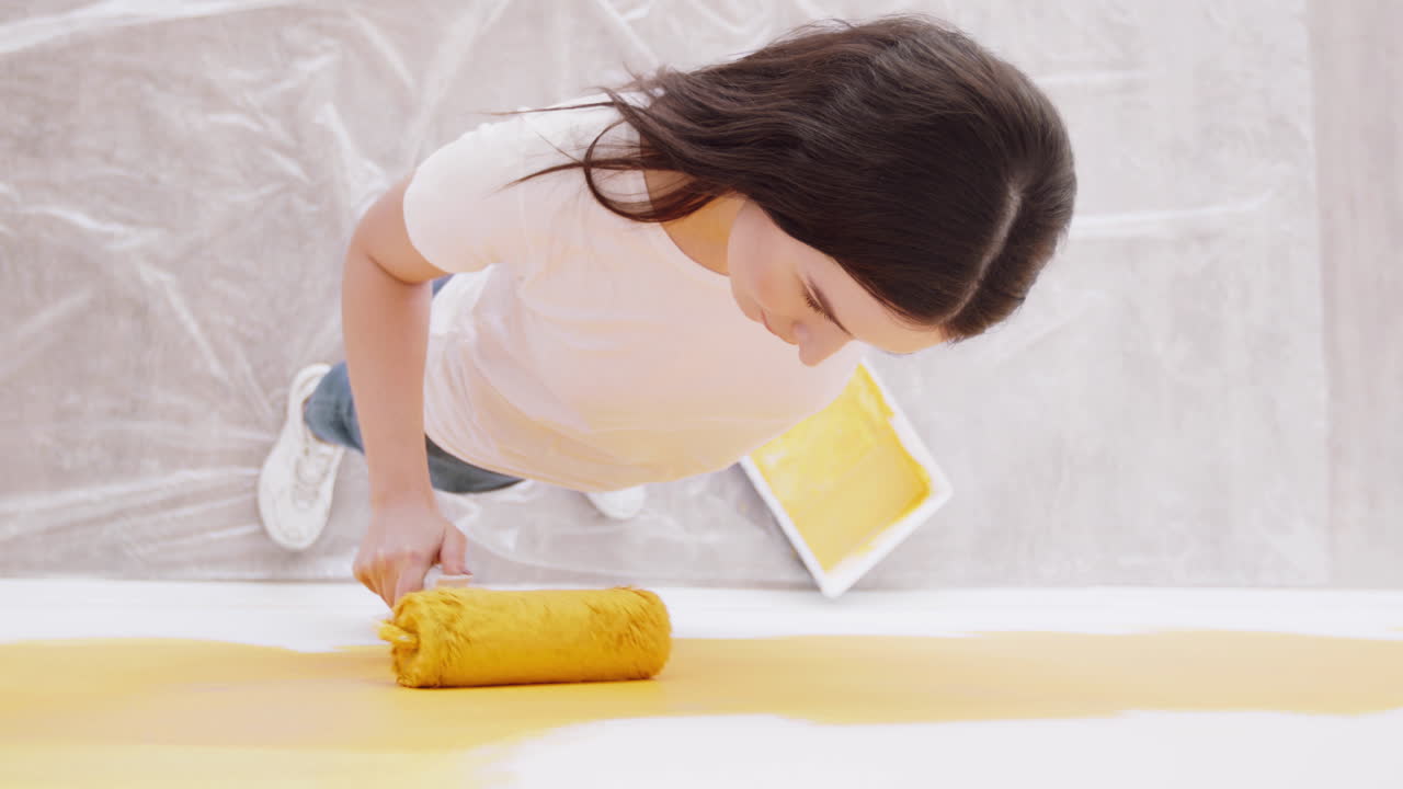 페인트 롤러로 벽을 칠하는 여자