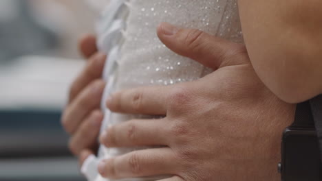 el marido abraza la cintura de la mujer con un elegante vestido blanco brillante