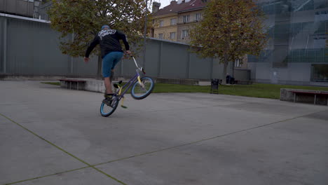 chico montando una bicicleta bmx, realizando el truco manual de peg en un skatepark