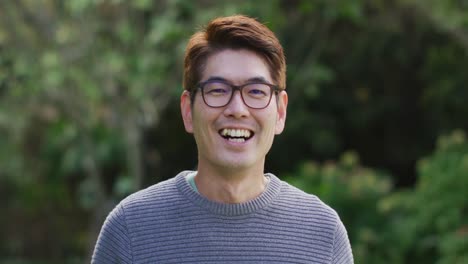 행복 한 아시아 사람 의 초상화 는 정원 에서 미소 짓고 웃고 있는 카메라 를 보고 있다