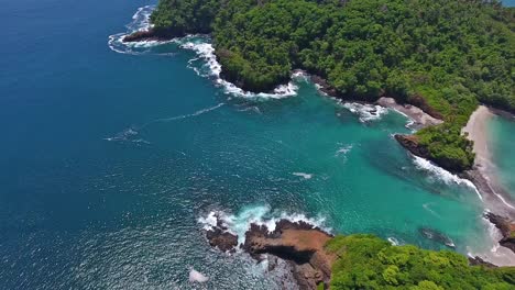 slow descent aerial of rocky coastline with blue water waves crashing