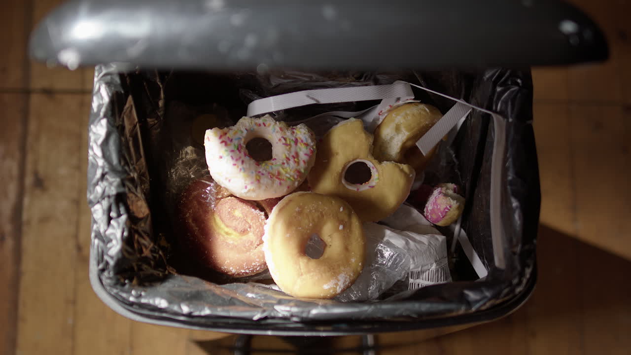 arrojar restos de comida chatarra y dulces en el contenedor para mejorar la dieta, pov de primer plano