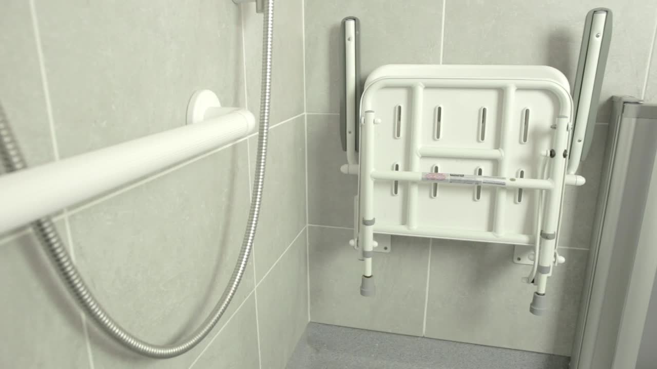 close up pan shot of foldable disabled shower seat inside wet area bathroom