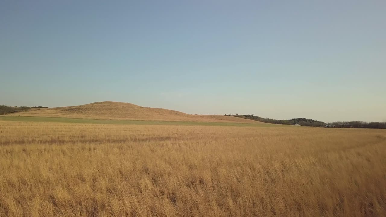 Aerial footage of control burn field fire with foothills in the distance