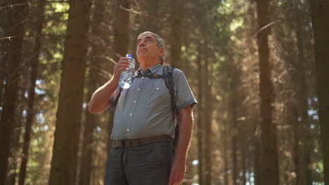 senior man drinking water in the forest
