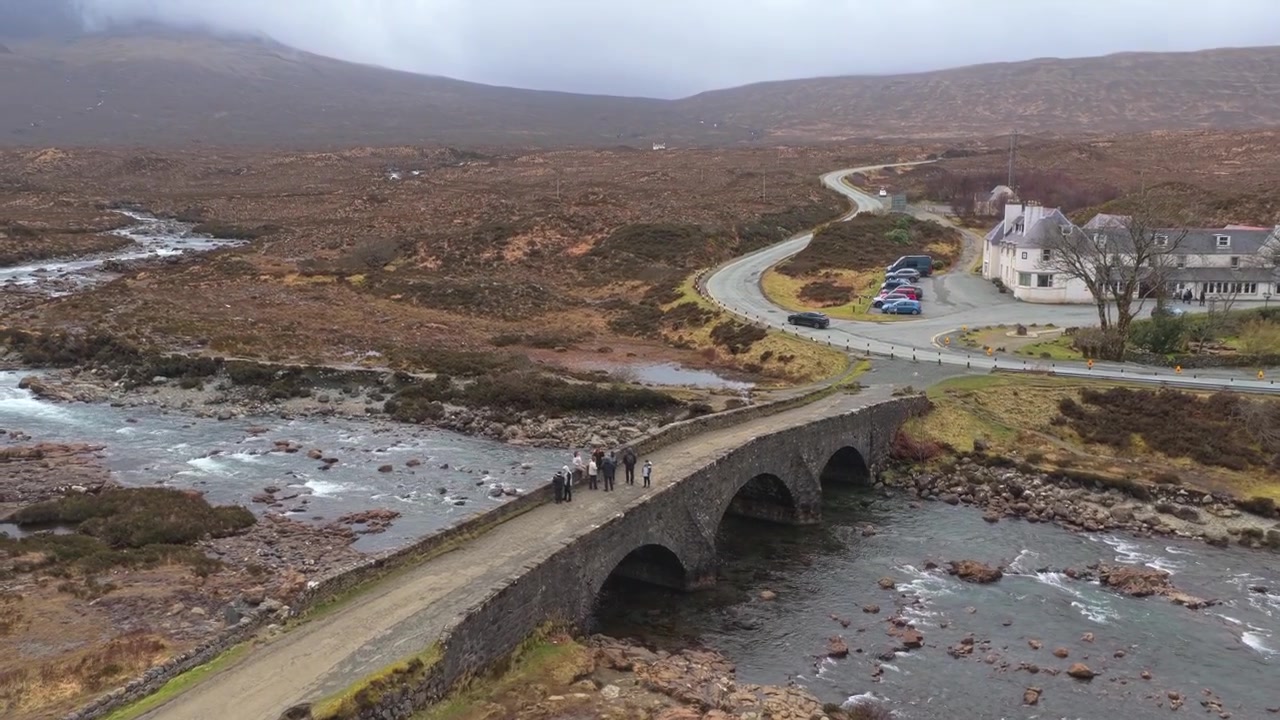 Luftfoto af den historiske Sligachan gamle bro, en ældgammel stenstruktur over en flod, omgivet af det store hedelandskab på Isle of Skye.