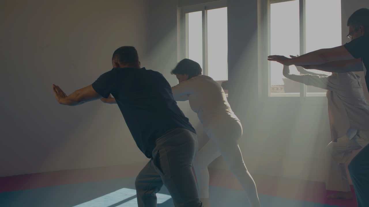 평화로운 노인들이 실내에서 타이 치를 연습하고 있습니다.