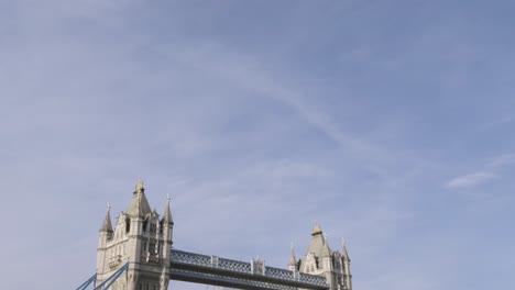 Tilting-down-to-Tower-Bridge-below-view-in-clear-sunny-day-with-car-traffic-and-tourists