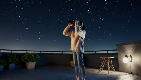 woman on rooftop gazing at the stars with binoculars