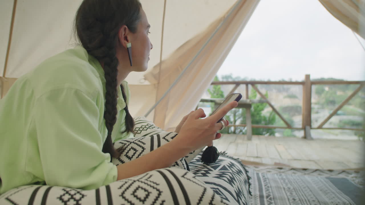 Woman Lying in Glamping Tent and Text Messaging on Phone