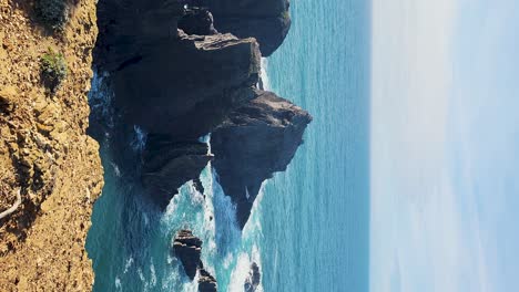 Zambujeira-Do-Mar-Sobre-La-Orilla-Del-Mar-Con-Olas-Del-Mar,-Acantilados-Y-Dunas-De-Arena-Cubiertas-Por-Vegetación-Verde-Hojas-Rojas-De-Higo-Amargo,-Día-Soleado,-Cielo-Azul-Claro