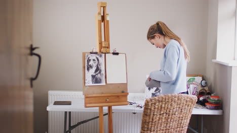 female teenage artist preparing to draw picture of dog from photograph