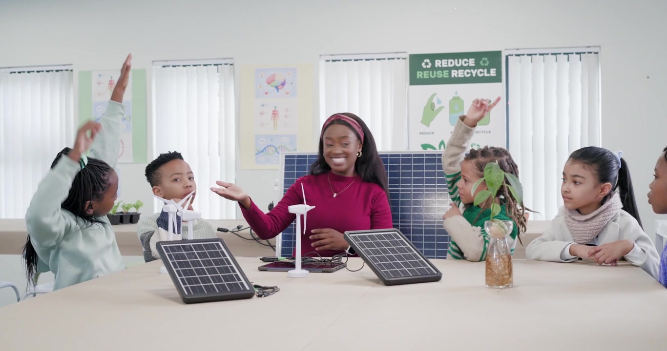 African American teacher pointing to solar panel, teaching renewables, inviting children to respond