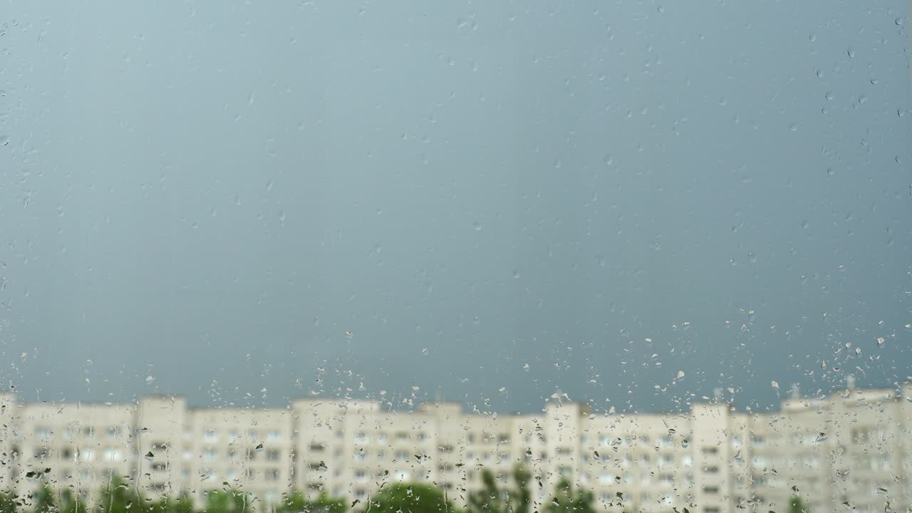 창문 유리 위에 물방울, 도시에서 여름 비, 파란 하늘, 집과 푸른 나무의 흐릿한 실루, 4k 비디오