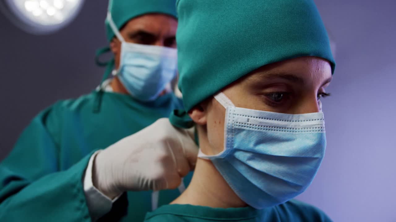 cirujano ayudando a una enfermera a atar la máscara quirúrgica en la sala de operaciones
