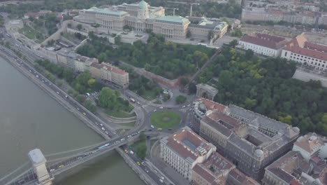 aerial view of roundabout city traffic near szechenyi chain bridge and parliament building. cars drive on circle road and riverside road. historic architecture buildings. budapest, hungary, europe