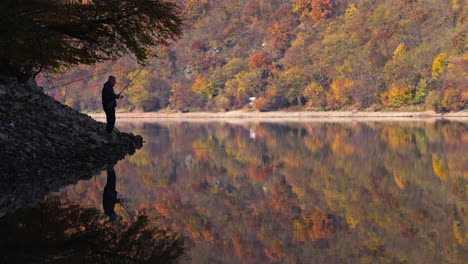 a fisherman enjoying a peaceful autumn day by the lake