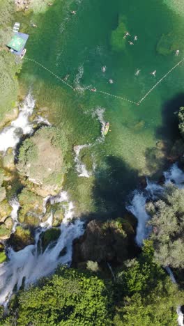 aerial birds eyr view of tourists enjoying the refreshing waters of kravica waterfall in bosnia and herzegovina during summer. vertical video