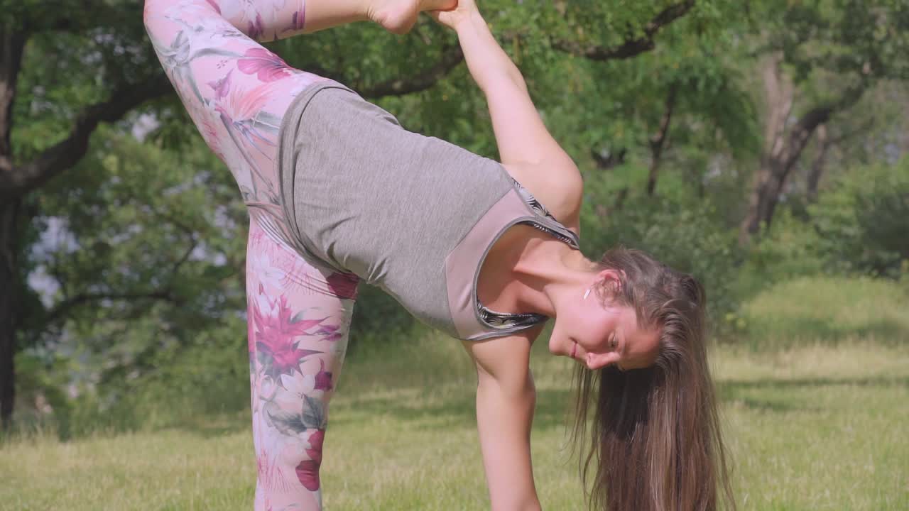 tiro inclinado hacia arriba de una mujer joven, realizando una pose de yoga con caña de azúcar, al aire libre
