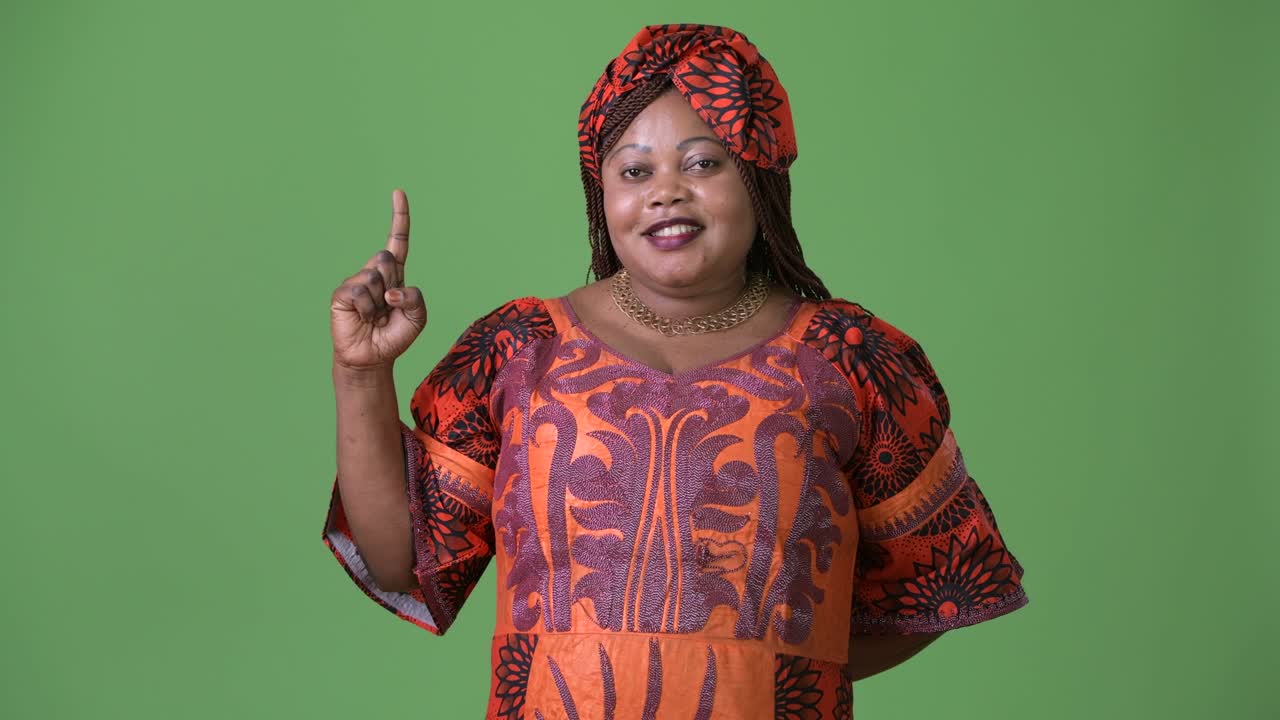una hermosa mujer africana con sobrepeso que lleva ropa tradicional contra un fondo verde