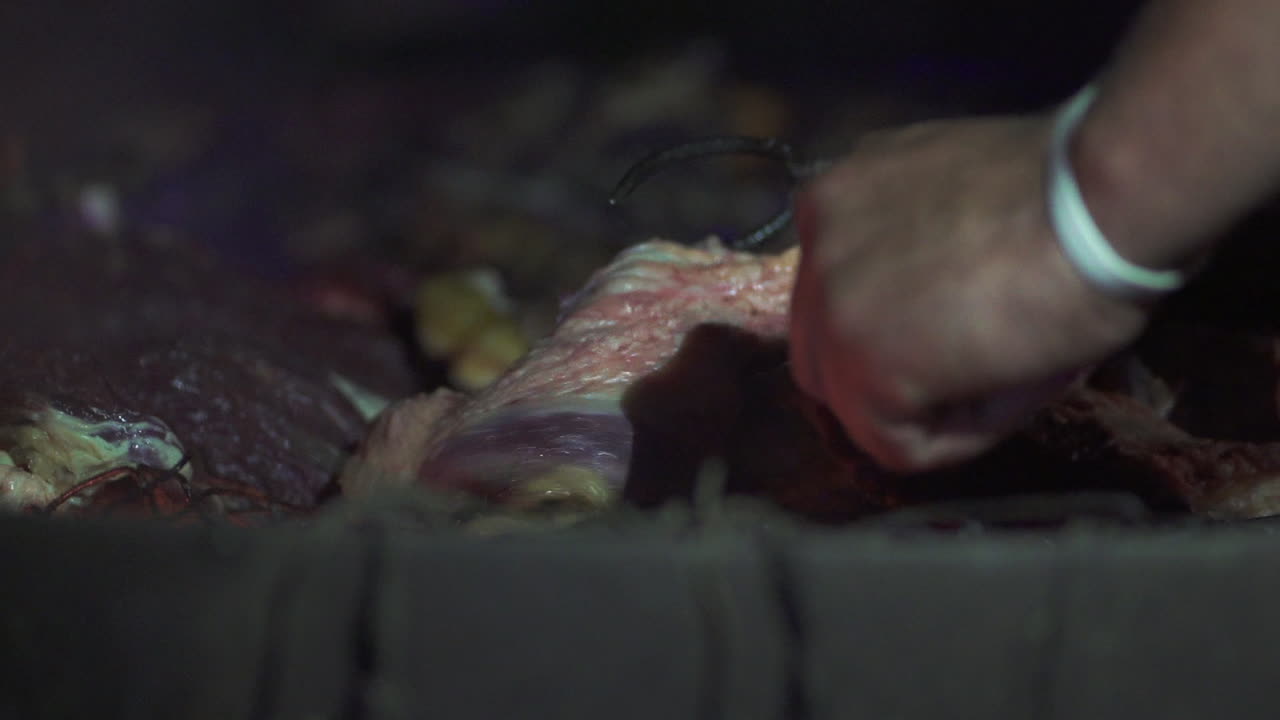 아르헨티나 의 아사도 에서 반이는 불꽃 위 에 어진 매운 고기 를 손 으로 돌리는 것 - 느린 동작