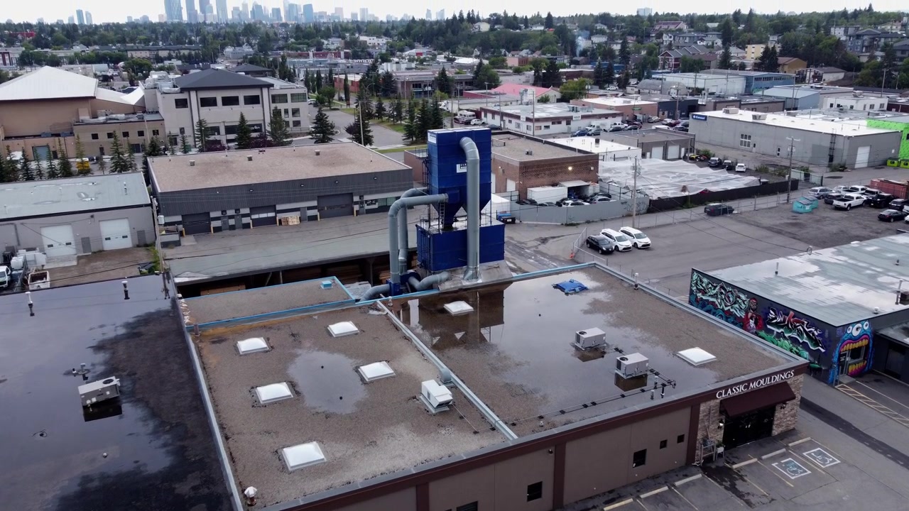 Industrielt støvopsamlingssystem på en industribygning, set fra luften med byens skyline, drone 4K.