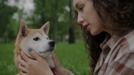 woman petting her shiba inu dog in the park