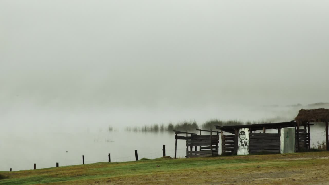 niebla brumosa matutina sobre el agua en el río además de un patio con una vieja choza en ruinas en el valle sagrado, cusco, tiro panorámico al amanecer
