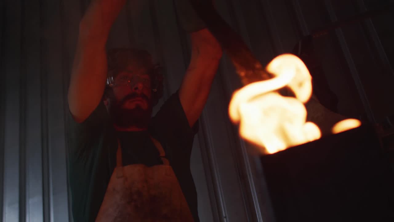 hombre caucásico herrero calentando cuchilla de metal en el horno en el taller