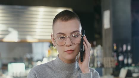 una mujer joven hablando por teléfono en un café.