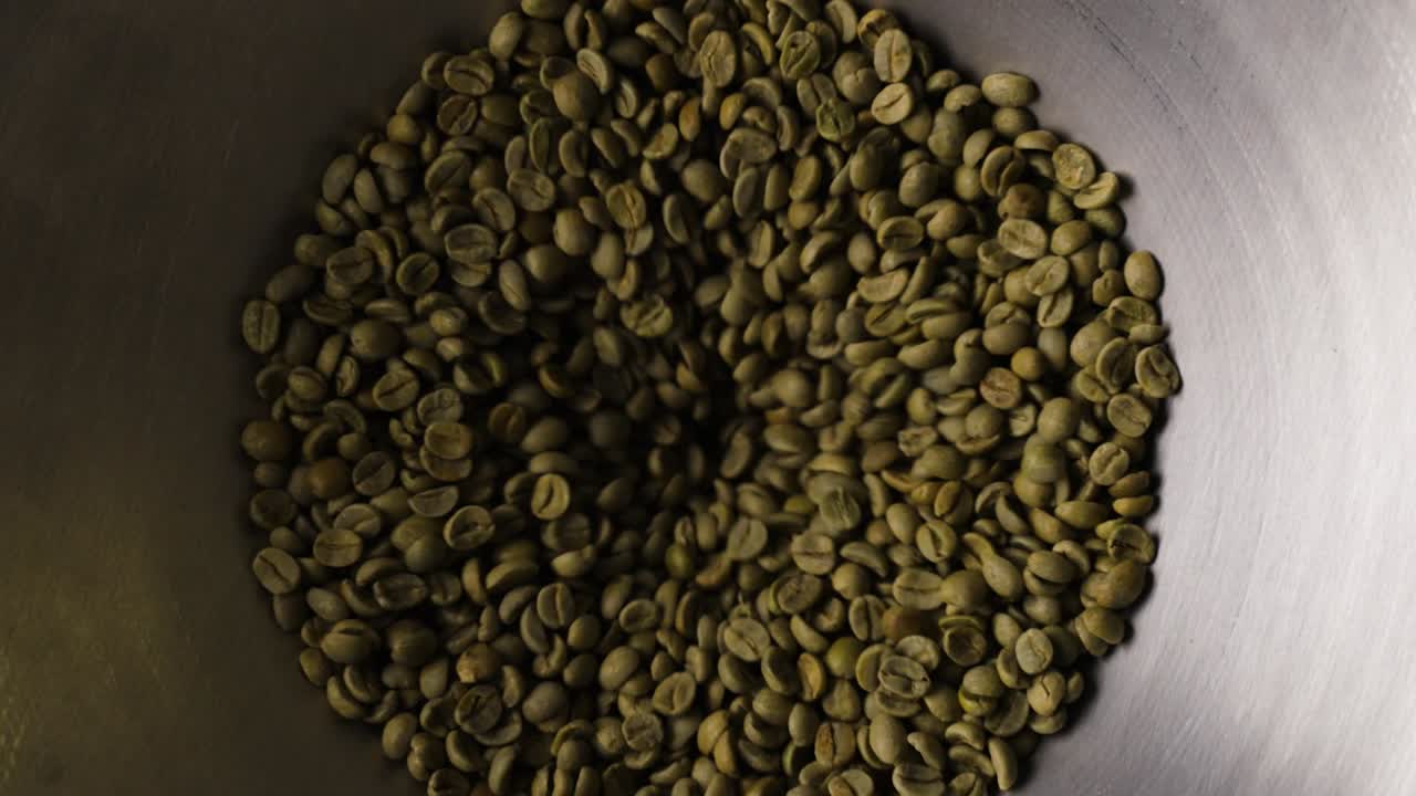 Granos de café antes de ser tostados, siendo introducidos en el tostador de tambor.
