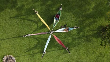 Aerial-view-of-couple-resting-on-hammocks-in-lush-park