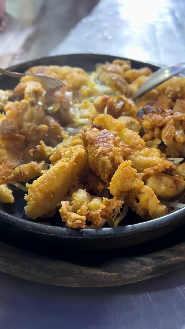 Primo piano di ostriche fritte mangiate con forchetta e cucchiaio su una padella fumante di notte