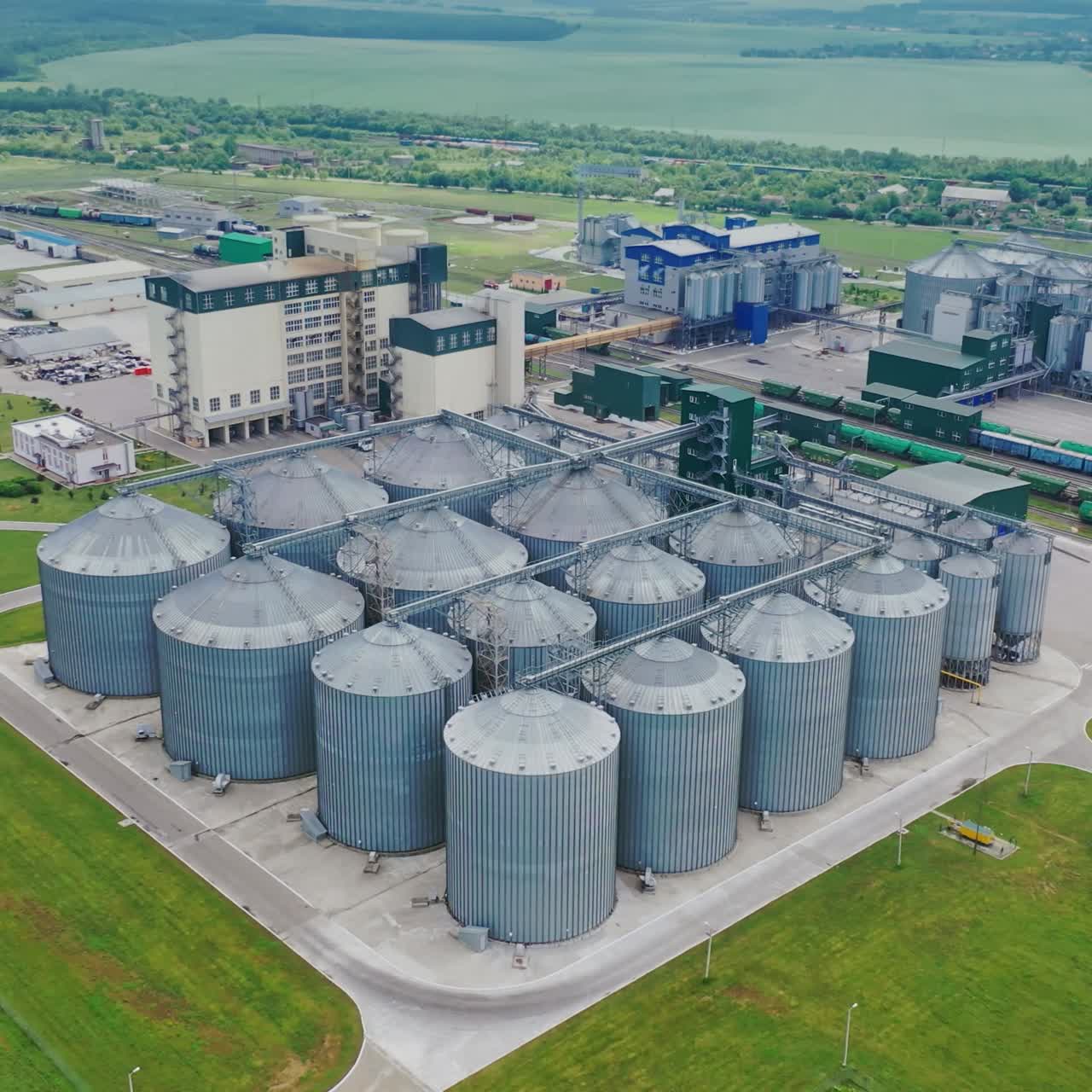 Silver bins for grain storage. Grain elevators on field. Modern granaries in farmland. Agribusiness concept. Aerial view.