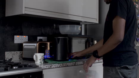 hombre indio adulto tomando una bolsa de té del cajón de la cocina y tirándola en una taza y esperando