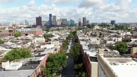 cinematic aerial pullback reveals expanse of baltimore skyline from federal hill neighborhood, colonial historic houses line street during summer day