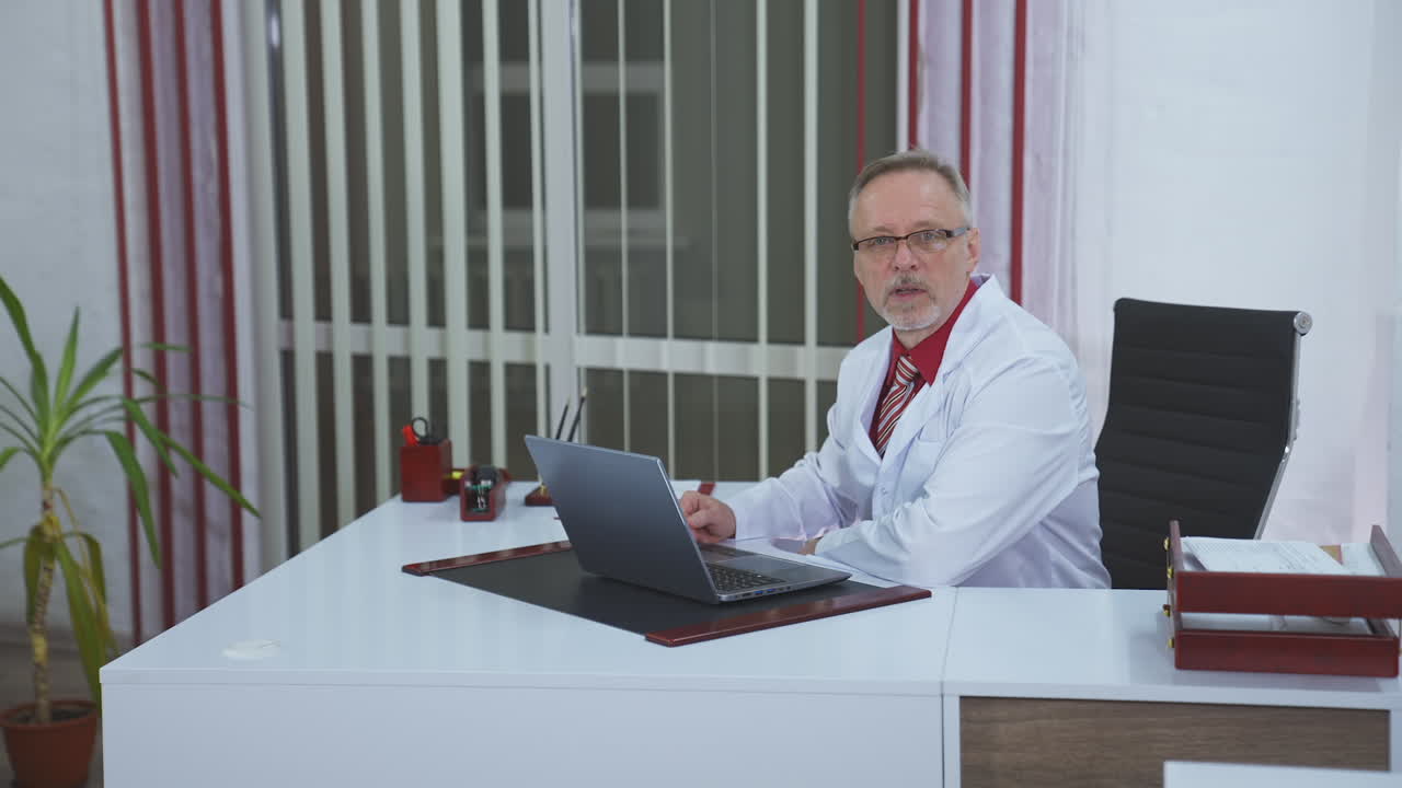 General practitioner sitting at his desk in medical office. Discussing medical issues.