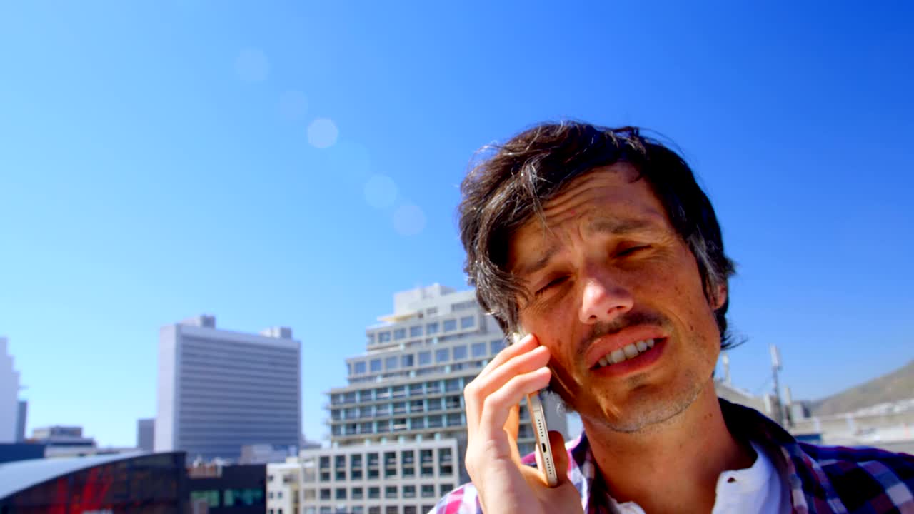 테라스 4k에서 휴대 전화로 이야기하는 남성 사진작가