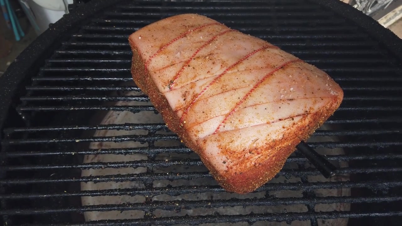 Mannlige hender plasserer en krydret rå svineribbe med rutet svor på en varm grill. Utendørs matlaging av røkt kjøtt til en sommerpiknik.
