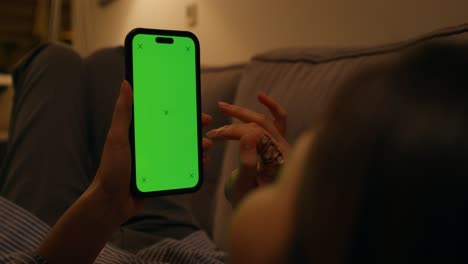 mujer usando un teléfono con una pantalla verde en un sofá