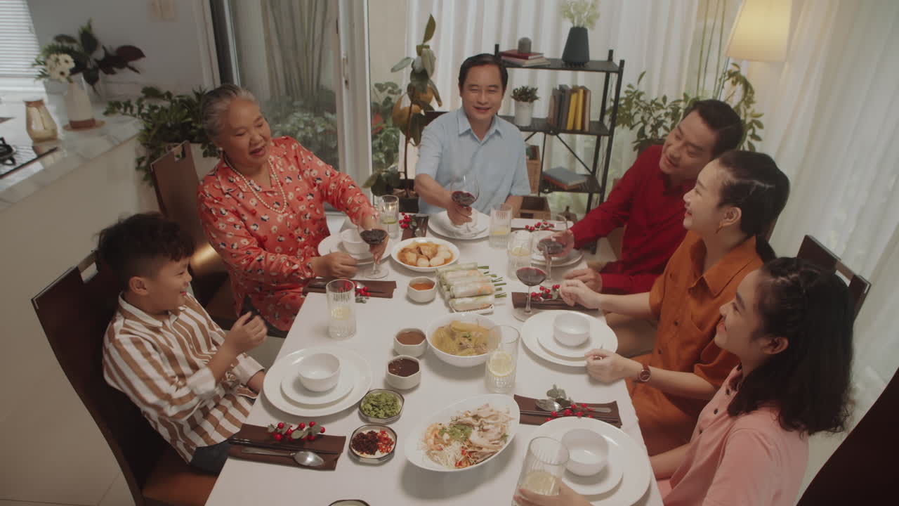 Big Asian Family Clinking Glasses at Table