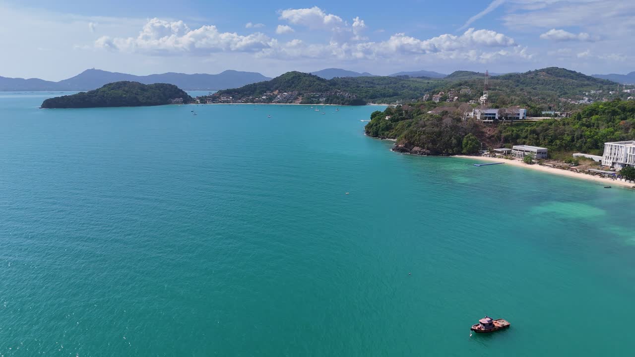 las imágenes de drones capturan la serena costa de phuket, tailandia, mostrando aguas turquesas, exuberante vegetación y resorts costeros bajo cielos despejados.