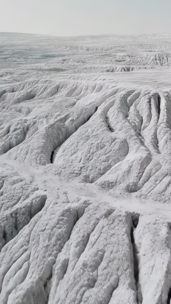 Video verticale: drone che scivola rivelando terrazze bianche e bacini su un altopiano, mostrando l'erosione